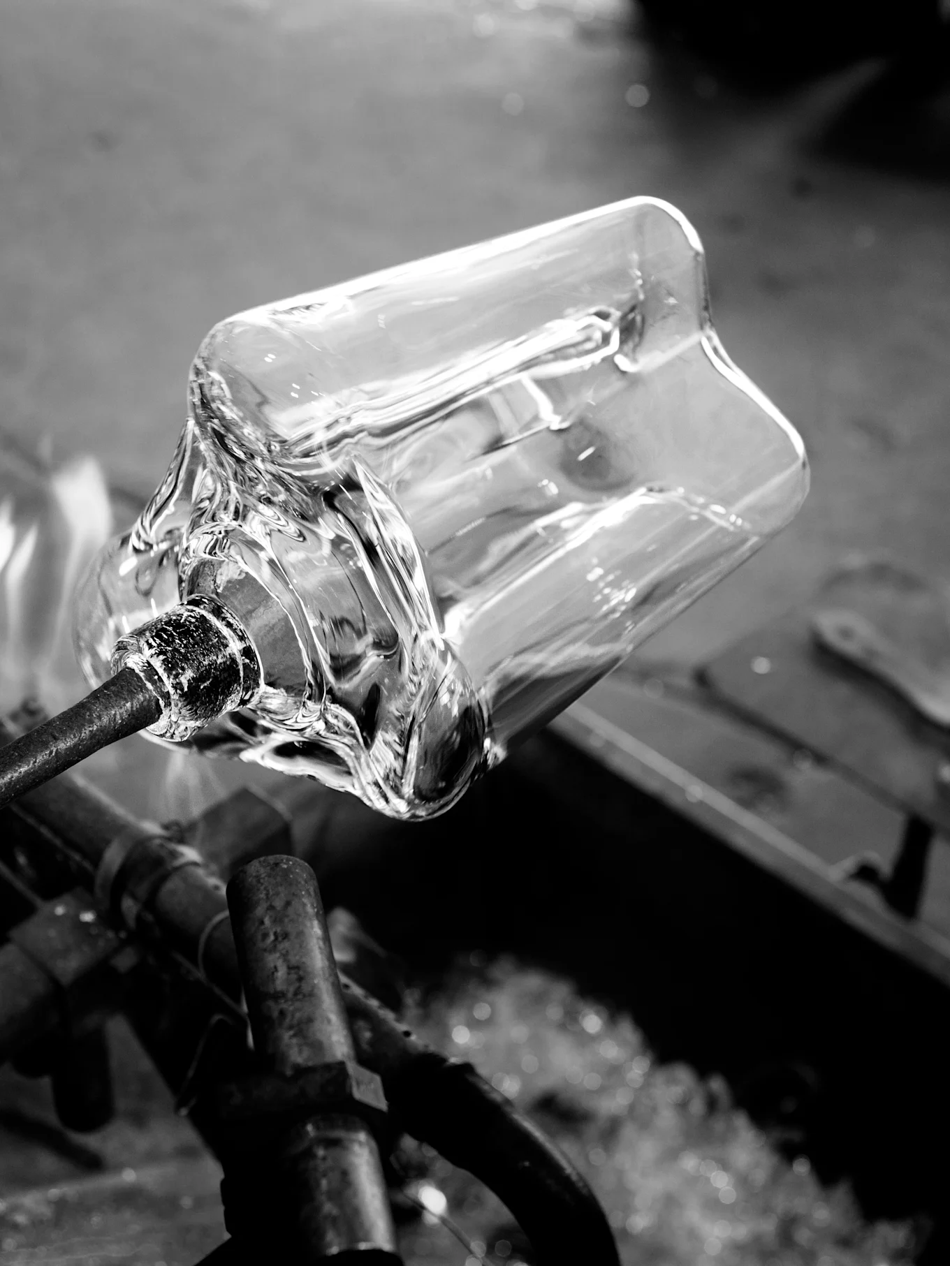 Klar glasbeholder formes på metalstang med varme, sort-hvidt.