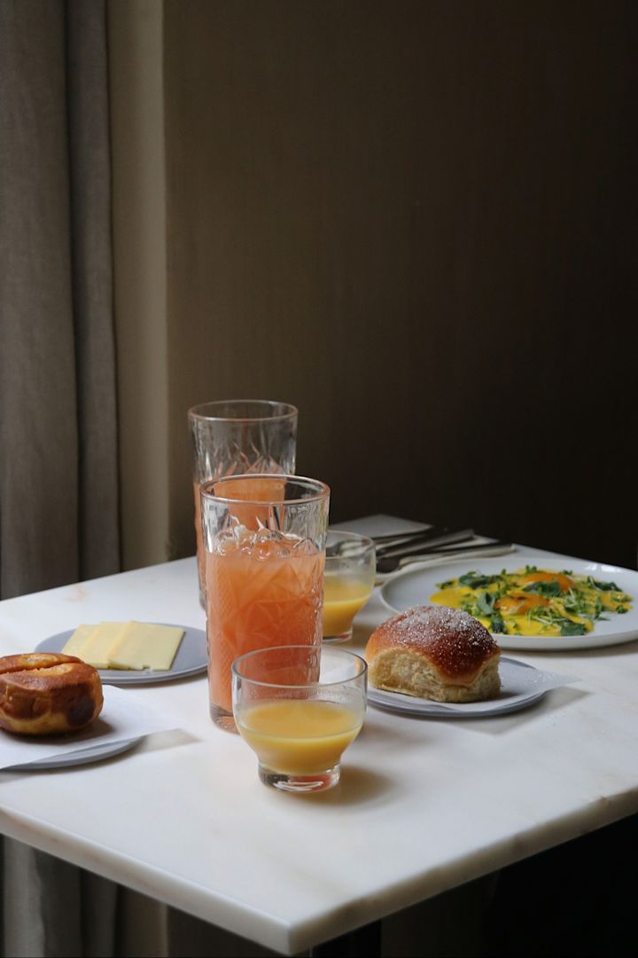Et bord dækket med mad og drikke på Restaurant Audo i København. Det er det ideelle sted at spise en bid mad ved frokosttid for enhver designelsker på tur i København. 