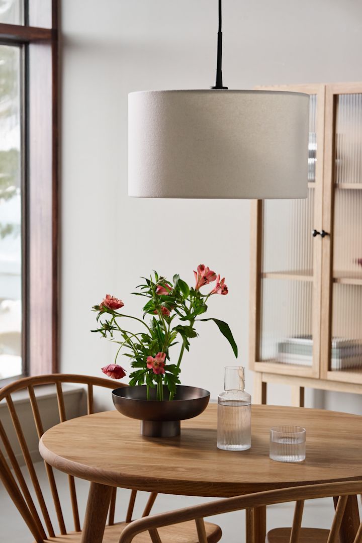Idéer til belysning i spisestuen for at fremhæve spisebordet. Her kan du se pendlen Soft fra Belid hængende over et træ spisebord.
