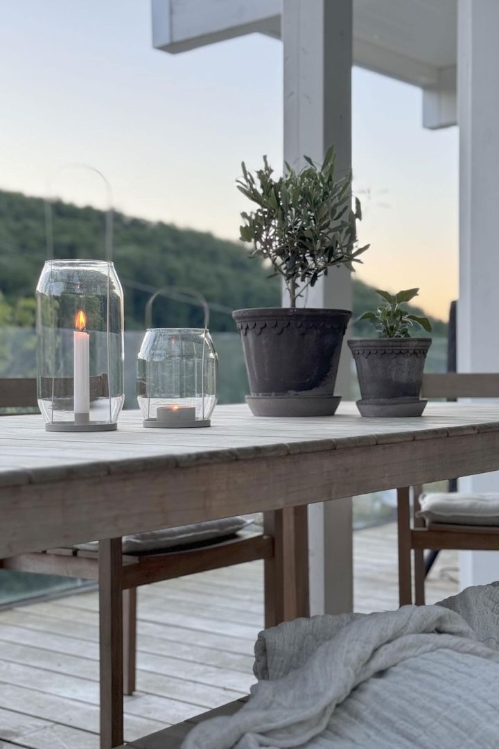 To grå Københavner-blomsterkrukker st�år på et bord ved siden af to Ernst-lanterner i forskellige størrelser på @zuhauseligs terrasse.