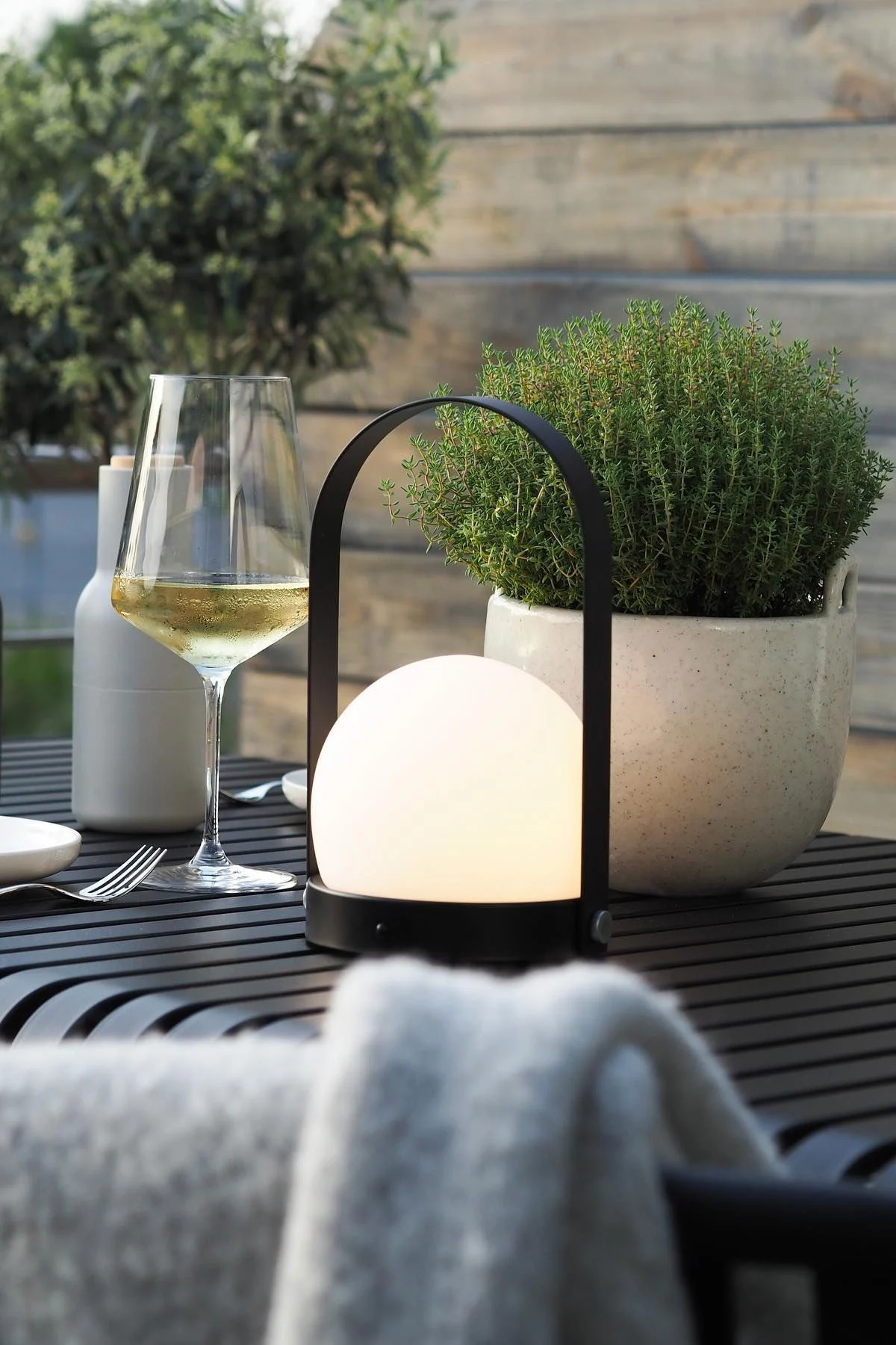 Den bærbare lampe Carrie fra Audo Copenhagen og urtepotten Speckle fra Ferm Living står på bordet Palissade fra HAY på @wohngluecksiebens terrasse.