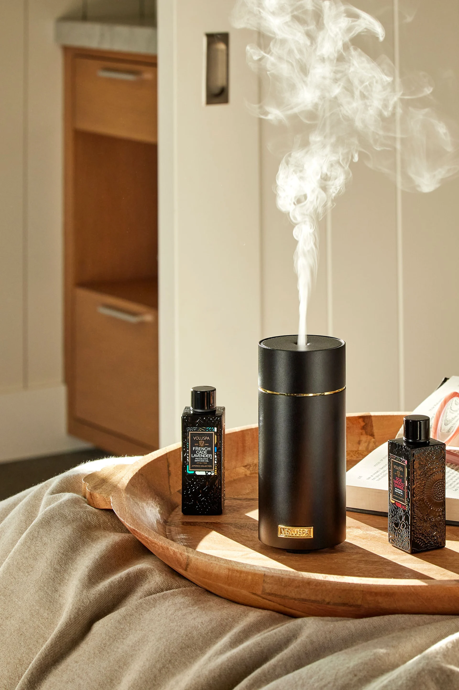 Den grå stendiffusor fra Volant står på en bunke bøger foran et spejl med en plante ved siden af. Giv den som gave på mors dag for at skabe en spa-følelse.