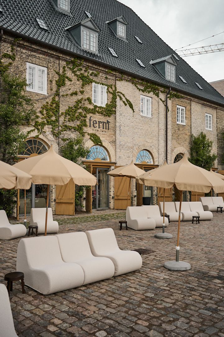 Området, hvor ferm LIVING holder til, bør man ikke gå glip af på en københavnsk byguide for designelskere. Her ser du den renoverede bygning fra det 18. århundrede med modulsofaer og parasoller udenfor. 