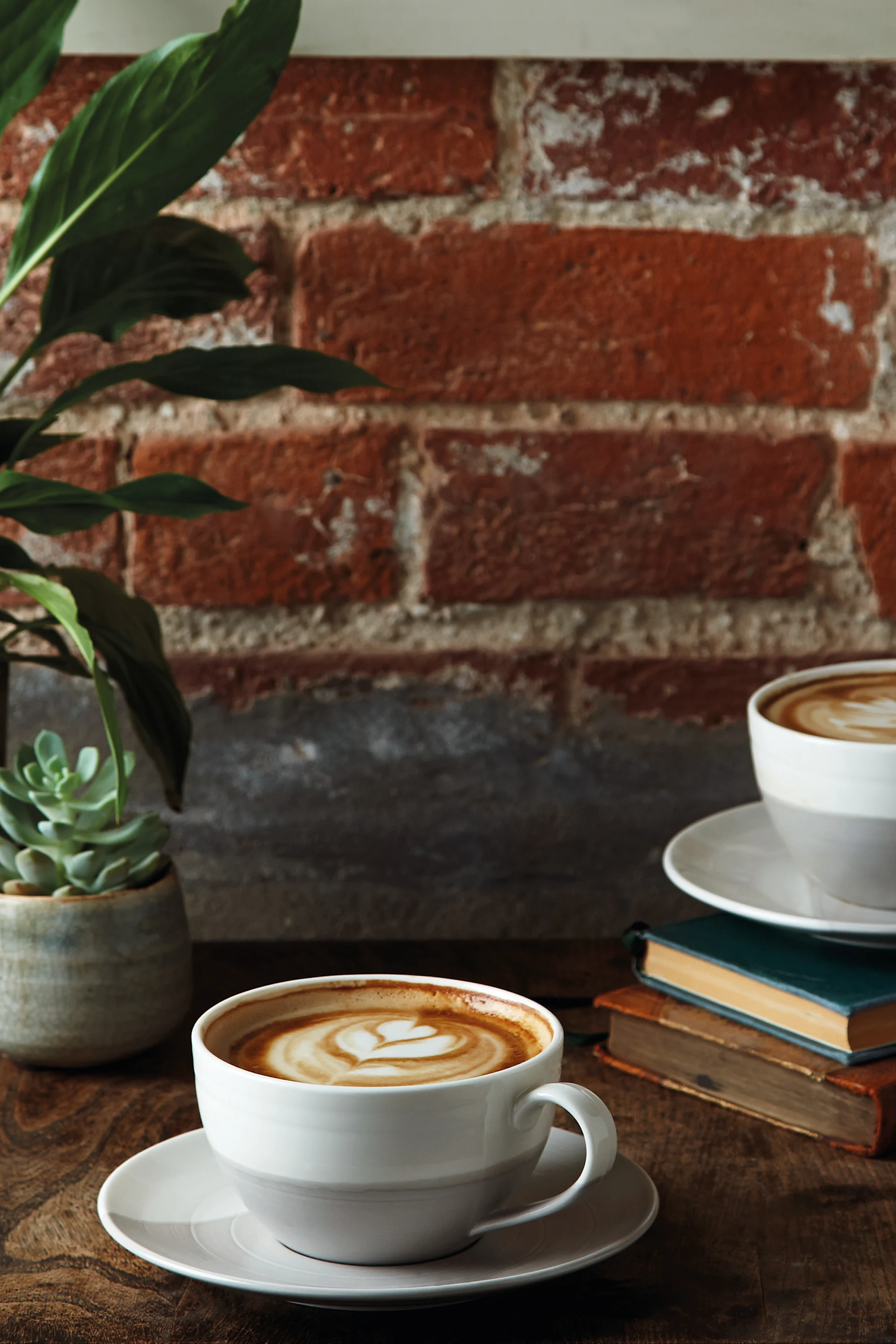 Den grå Coffee & More espressokop står på en træbakke på en seng med en croissant ved siden af.