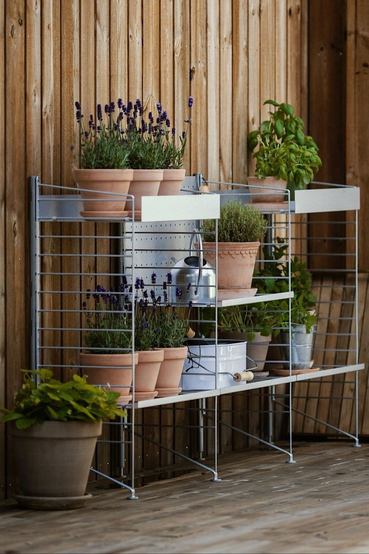 En udendørs hylde fra String står på @applauddens terrasse, fyldt med forskellige planter i Bergs Potters blomsterpotter fra Københavner-kollektionen.