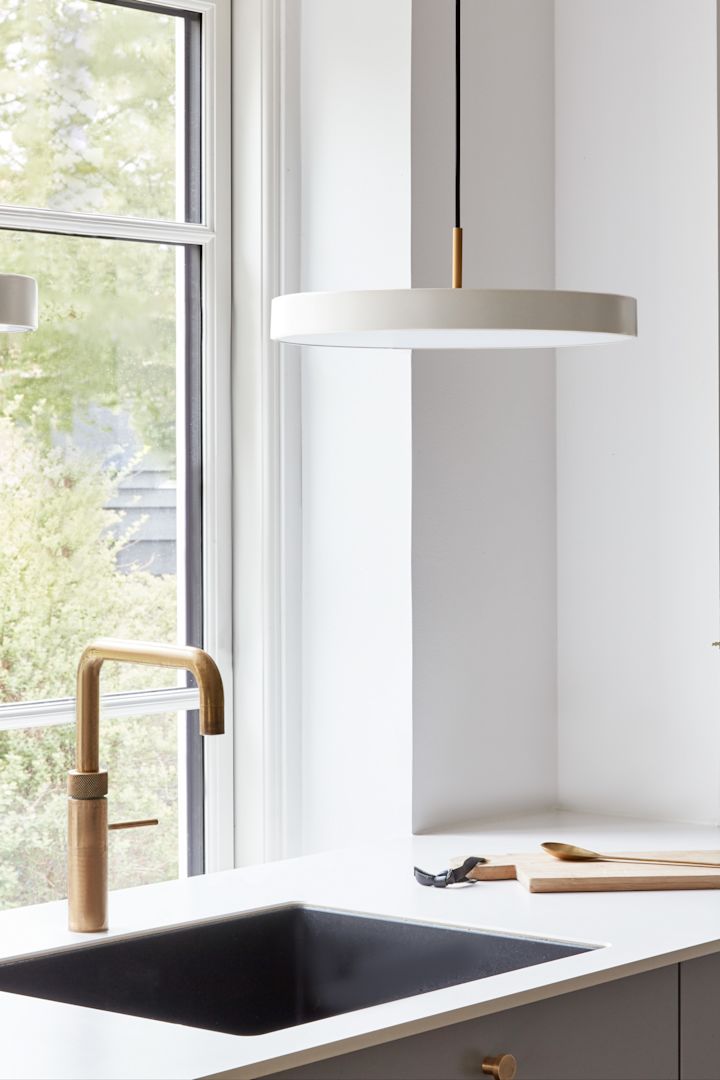 Brug store pendler, hvis du har brug for lidt mere lys på steder som vasken. Her ses Asteria Micro-pendlen i perlehvid fra Umage hængende over en vask.