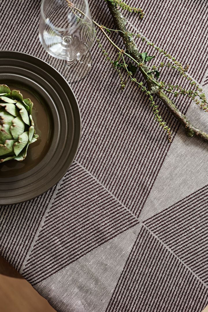 Den geometriske borddug fra NJRD i brun med en brun lines tallerken og en grøn artichoke.