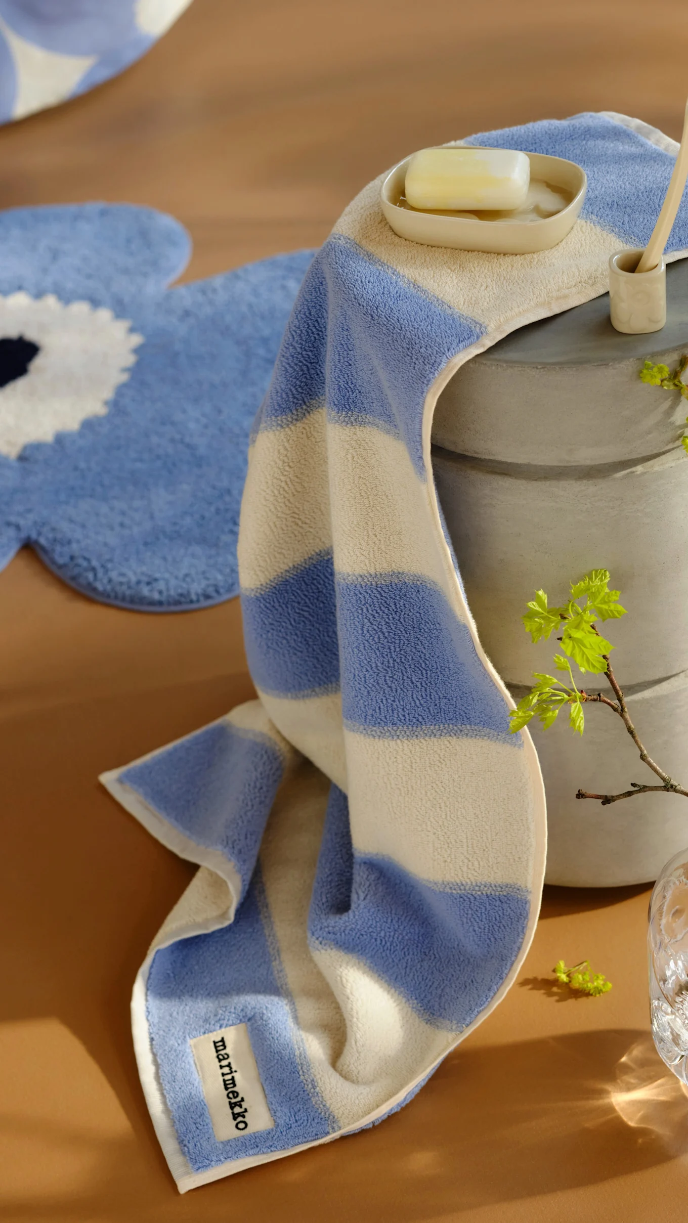 Stak af fire puder med abstrakte og blomstrede mønstre i beige, pink og sort på en træskammel. En anden mønstret pude ligger på gulvet.