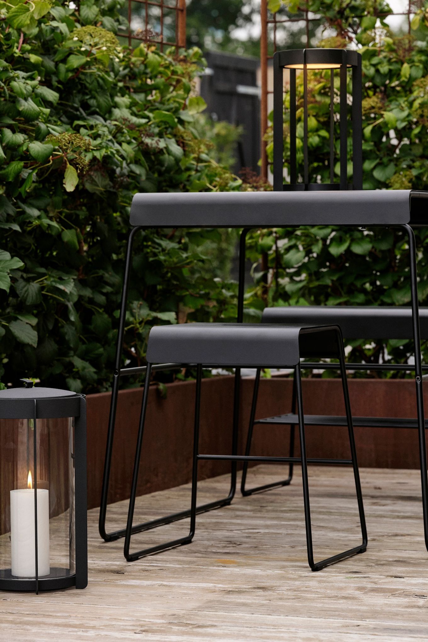 Bordet og skamlen fra Zone Denmarks udendørskollektion kan placeres ude på en terrasse.