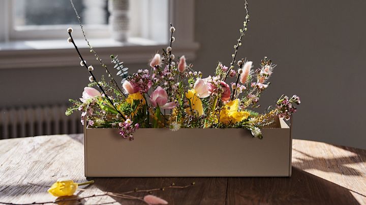 Lille beige Plant Box fra ferm LIVING der står på bordet med forårsblomster i som inspiration til interiør design til foråret. 