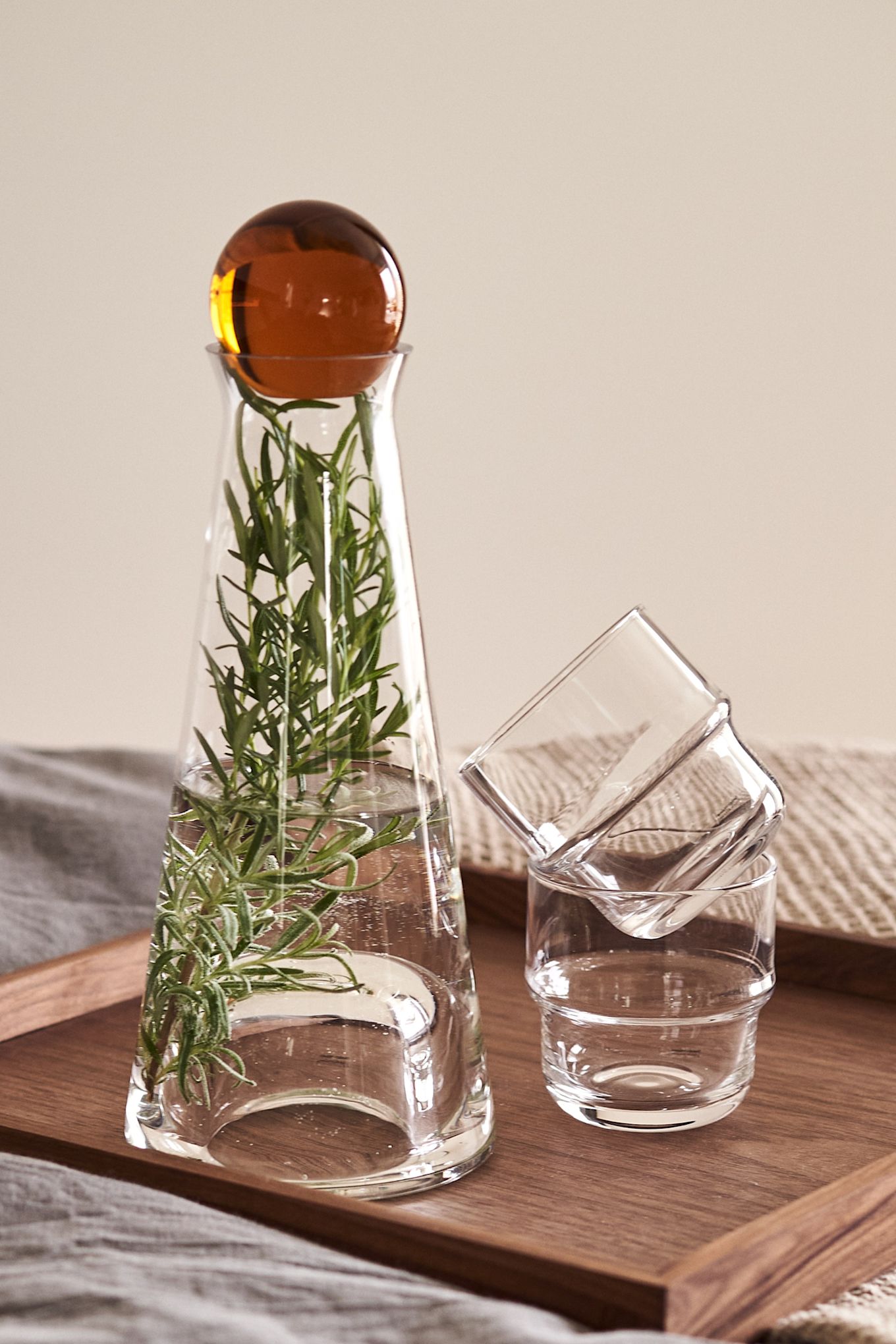 Her kan man se Fia karaflen med rav kugle med en stilk af rosemarin med NM& glasene, alt fra Design House Stockholm.