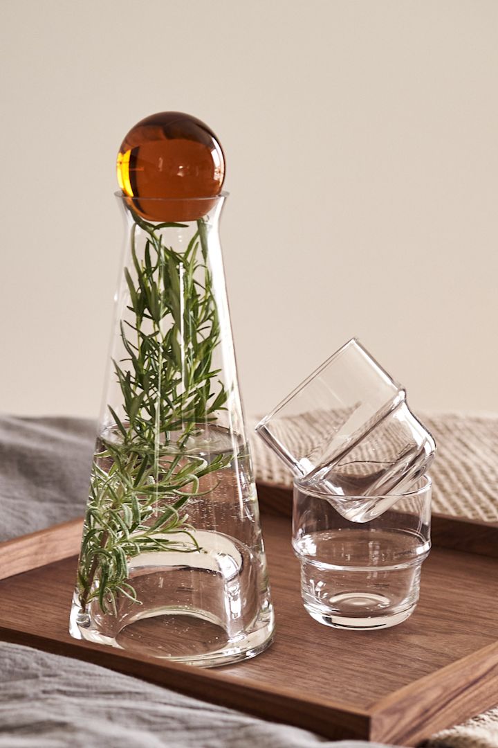 Her kan man se Fia karaflen med rav kugle med en stilk af rosemarin med NM& glasene, alt fra Design House Stockholm.