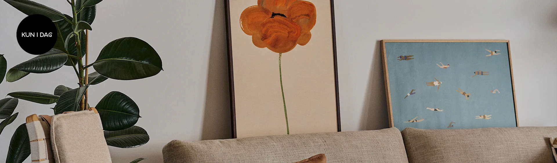 Stue med beige sofa, stor grøn plante med 'KUN I DAG' skilt, orange blomsterbillede, og billede med svømmere.