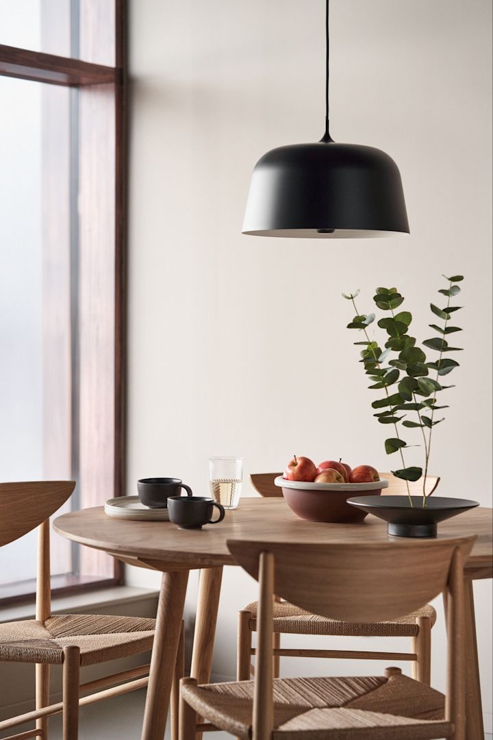 Opfrisk dit hjem med moderne loftsbelysning. Her ses loftslampen Halo fra Scandi Living i farven sort hængende over et rundt spisebord.  