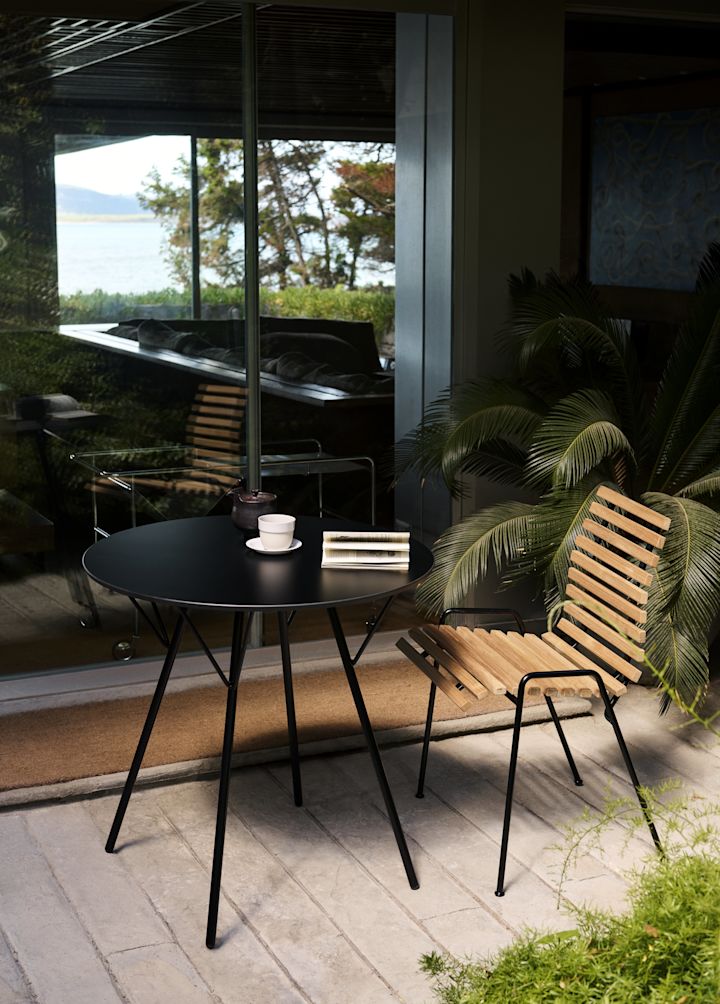 RFH RD4 patio side chair fra &Tradition står udenfor med et rundt bord.