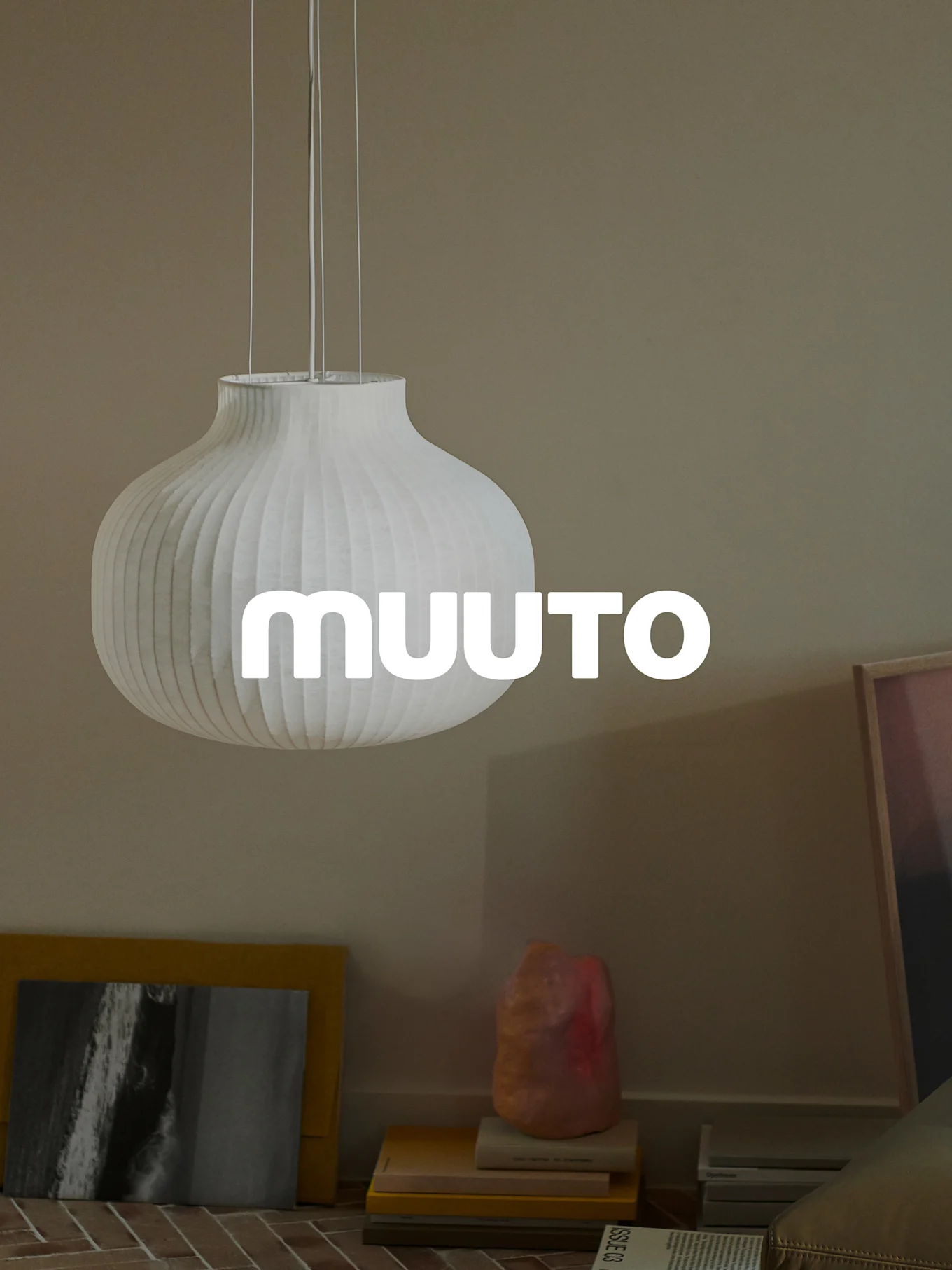 Hvid, riflet græskarformet pendellampe med 'MUUUTO'-logo i et beige rum.