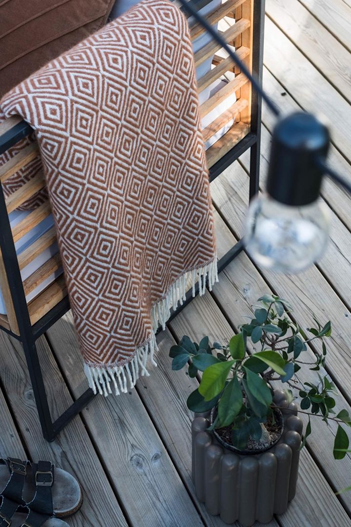 Den brune blomsterkrukke fra DBKD står på en terrasse ved siden af en bænk med et tæppe i @lindaz.se's hjem.