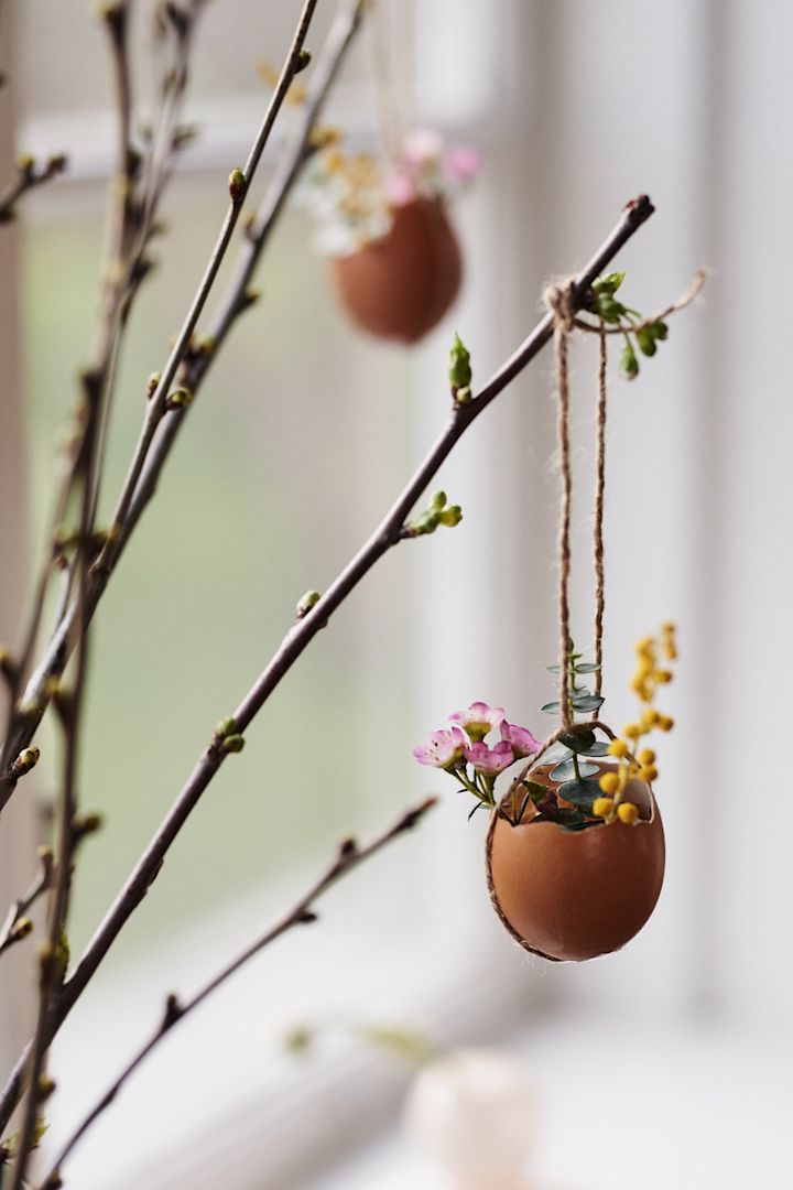 Påskehåndværk med æg og blomster i form af en lille kurv lavet af æggeskaller og fyldt med forårsblomster. 