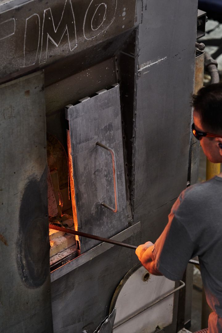 En mand putter glas ind i en ovn i Iittalas glasfabrik i Finland.
