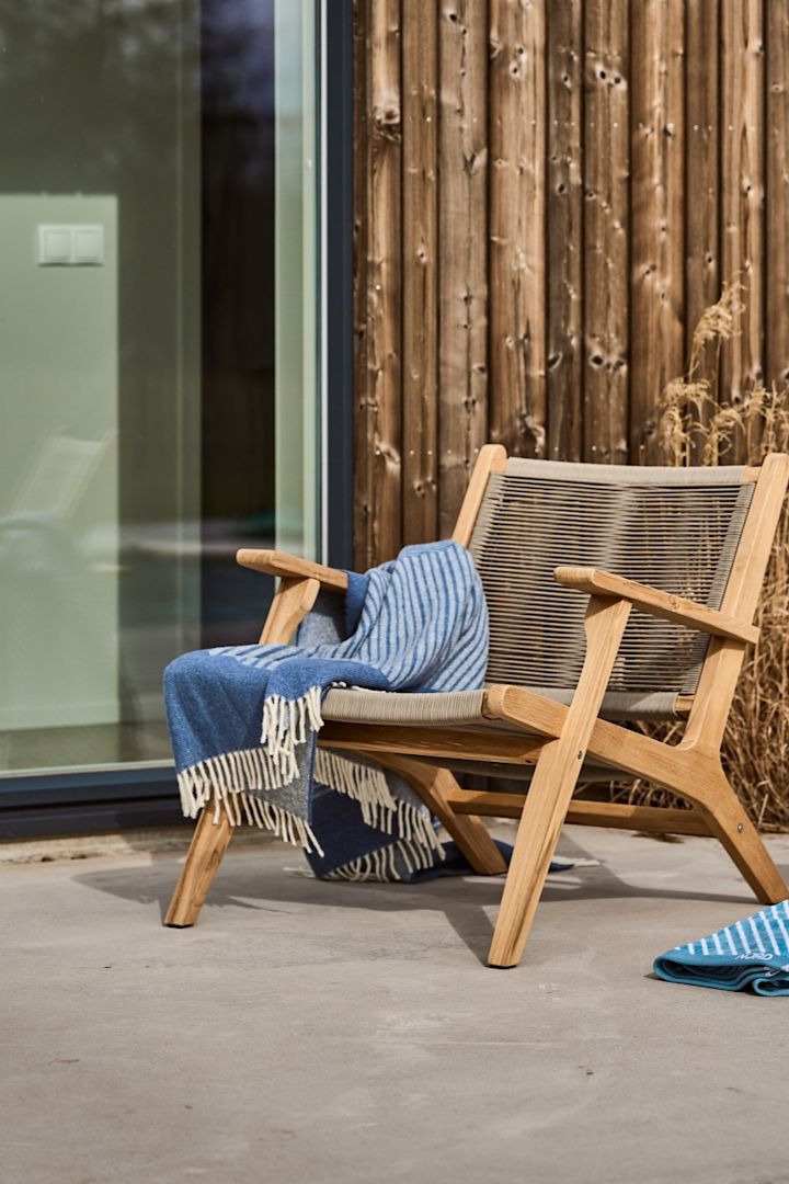 En skandinavisk terrasse med Sandvik-loungestolen fra 1898 og det blå Stripes-uldtæppe fra NJRD.