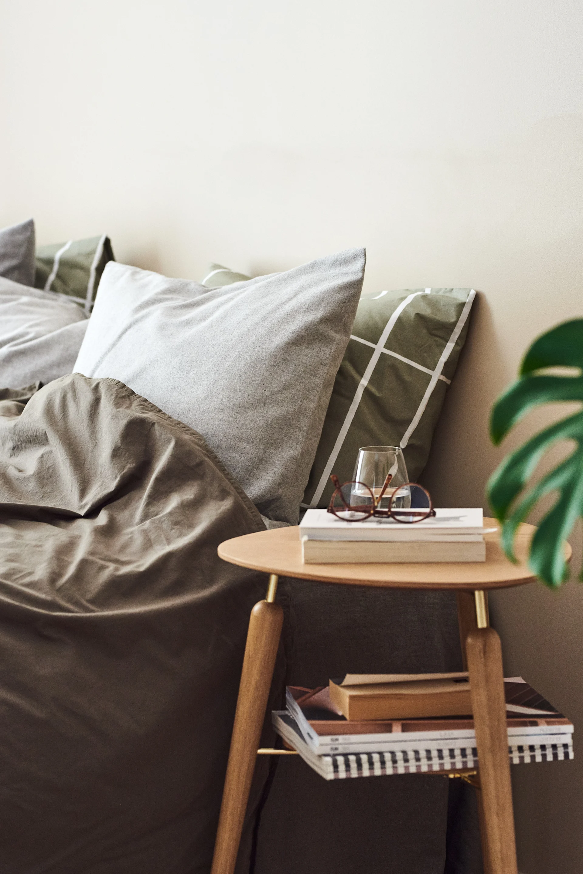 Et fint sidebord i træ og mæssing fra Umage i et grønt soveværelse, perfekt til at skabe hotelfornemmelser i soveværelset.