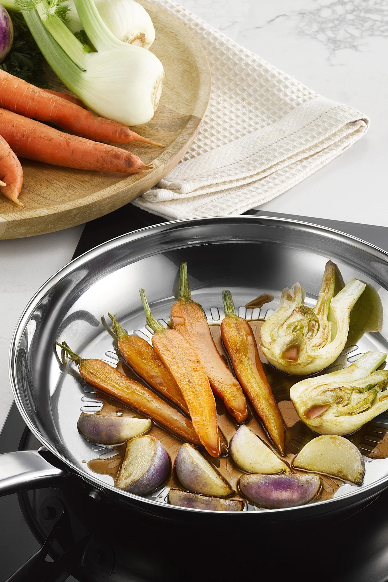 Forskellige grøntsager steges i Intuition Techdome-panden i rustfrit stål fra Tefal.