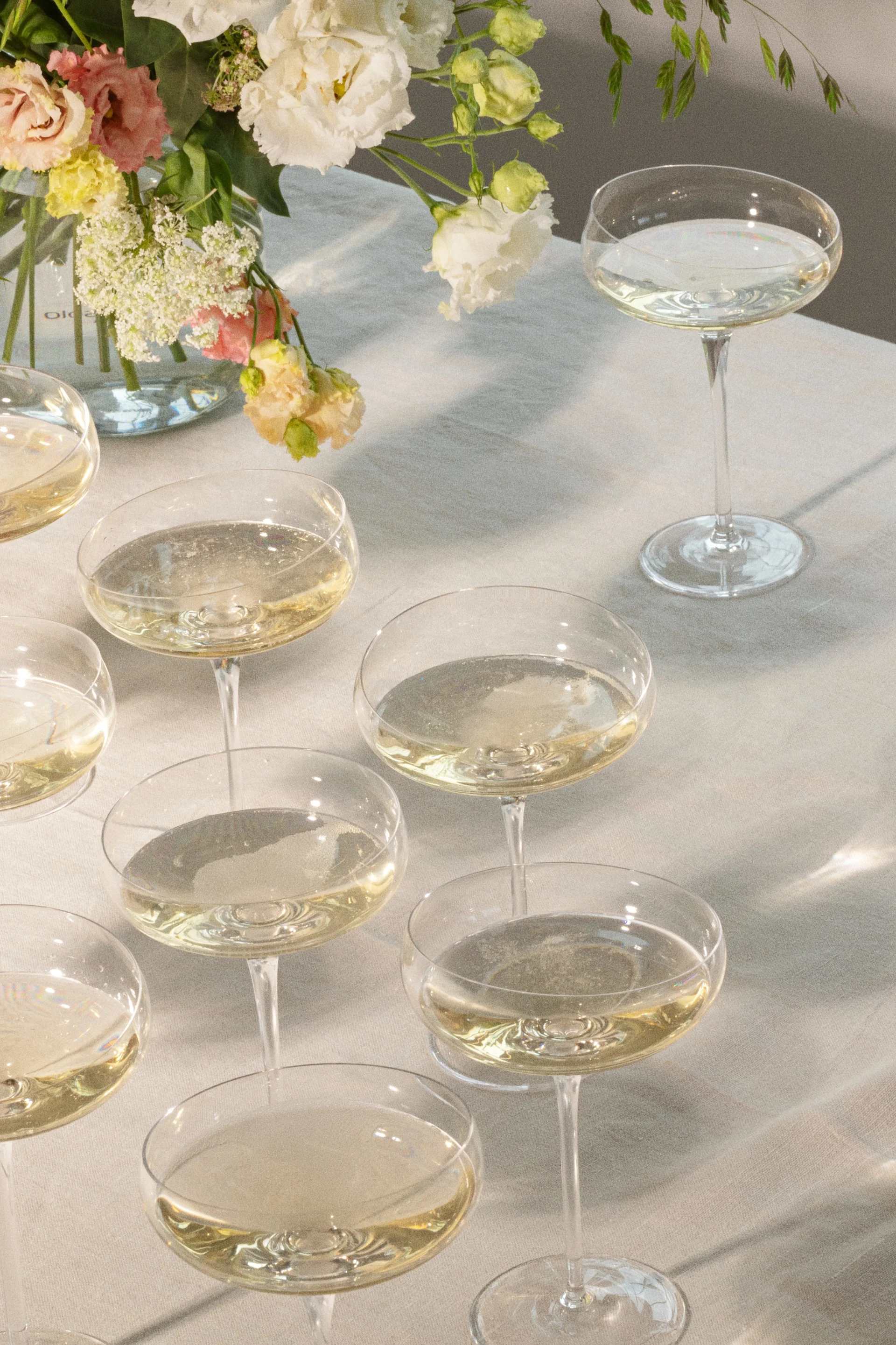 Champagneglas med mousserende drikke på et bord med blomsterarrangement.