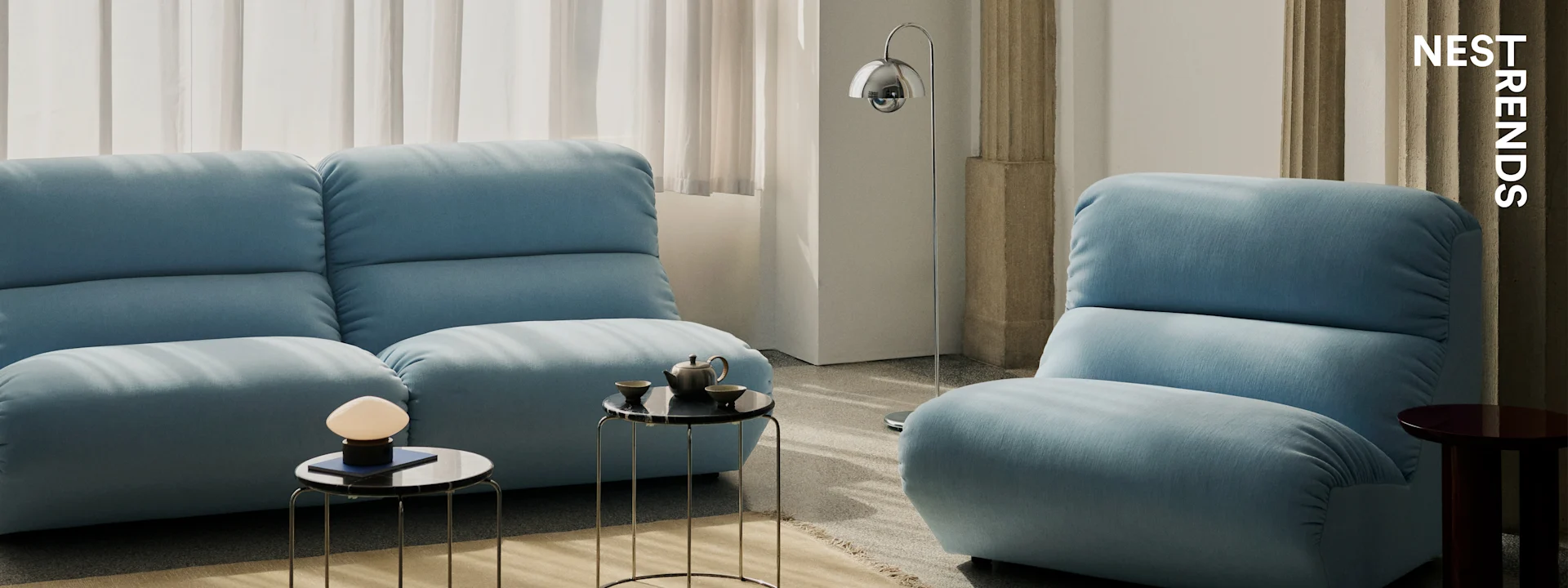 Moderne stue med to lyseblå sofaer, sorte marmorbordplader og elegante lamper.