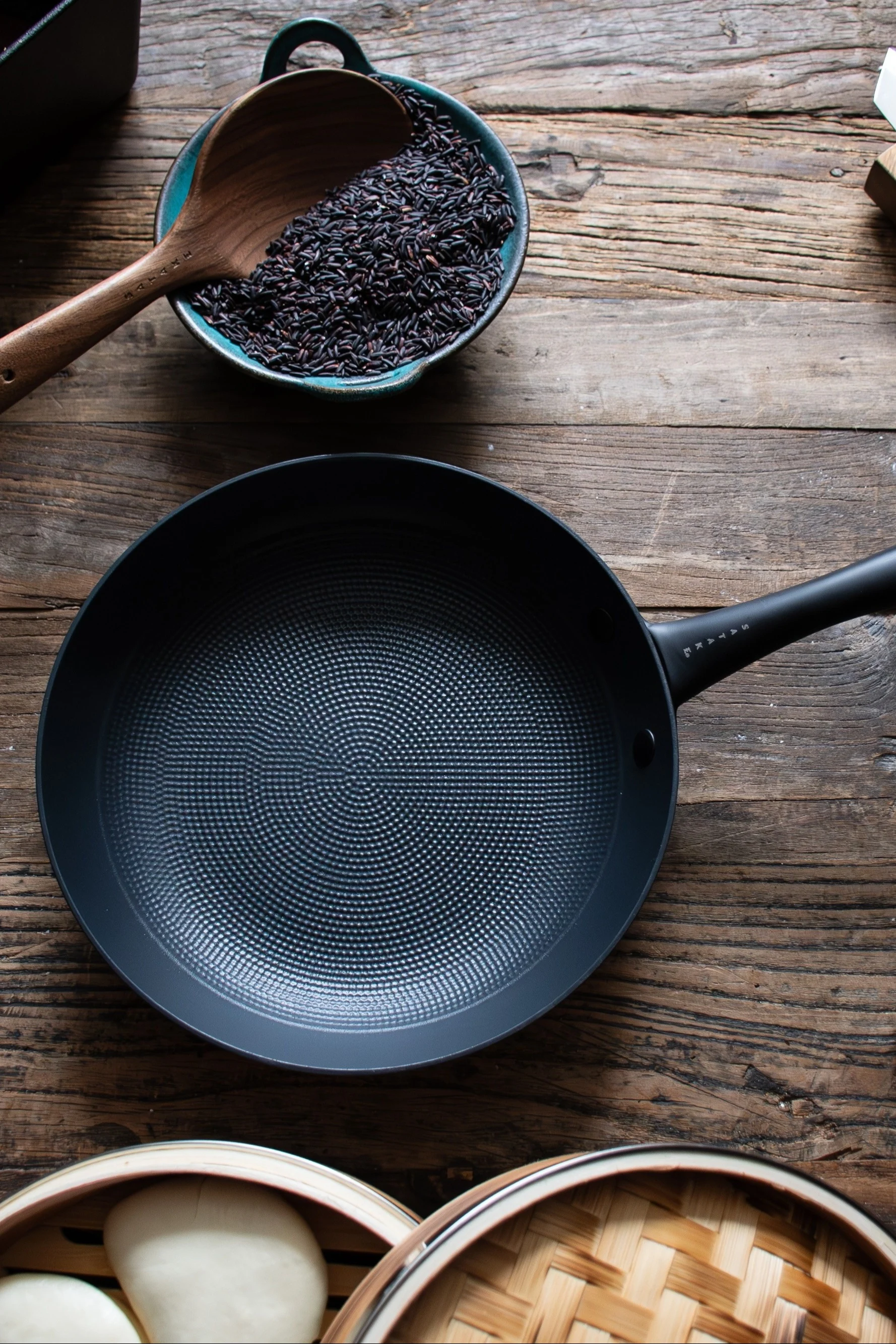 Satakes stegepande står på et mørkt træbord.