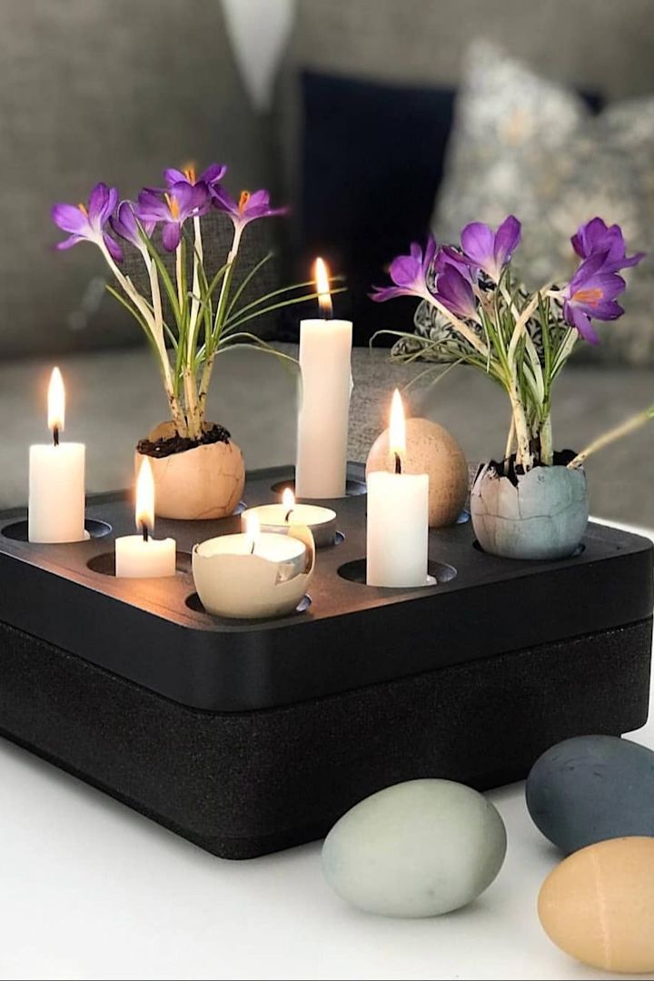 En sort Stumpastaken-lysestage fra Born in Sweden er pyntet med lys og farvede æg med blomster til påske. @dallasvillan