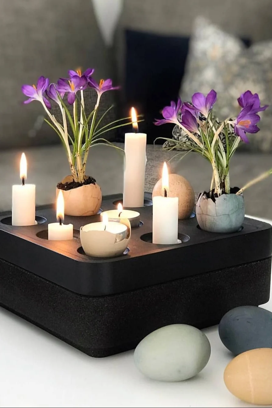 En sort Stumpastaken-lysestage fra Born in Sweden er pyntet med lys og farvede æg med blomster til påske. @dallasvillan
