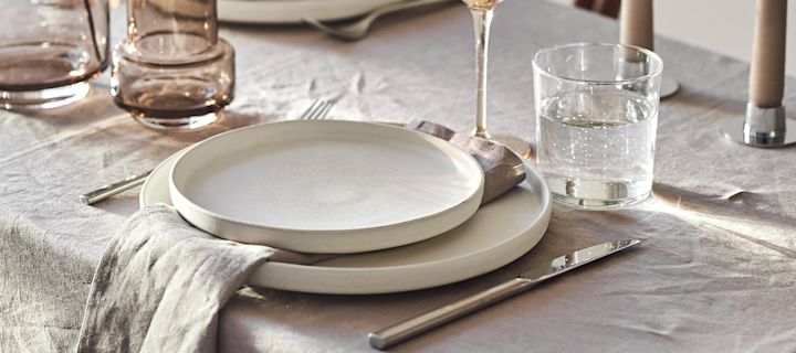 En elegant hvid borddækning med sprøde hvide servietter og dug og rent hvidt porcelæn fra NJRD.
