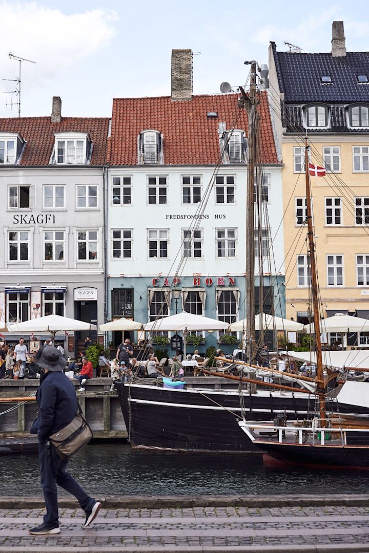 Et stop ved Nyhavn er et must på enhver tur i København. Her kan du se nogle der går forbi de farverige bygninger på havnen.