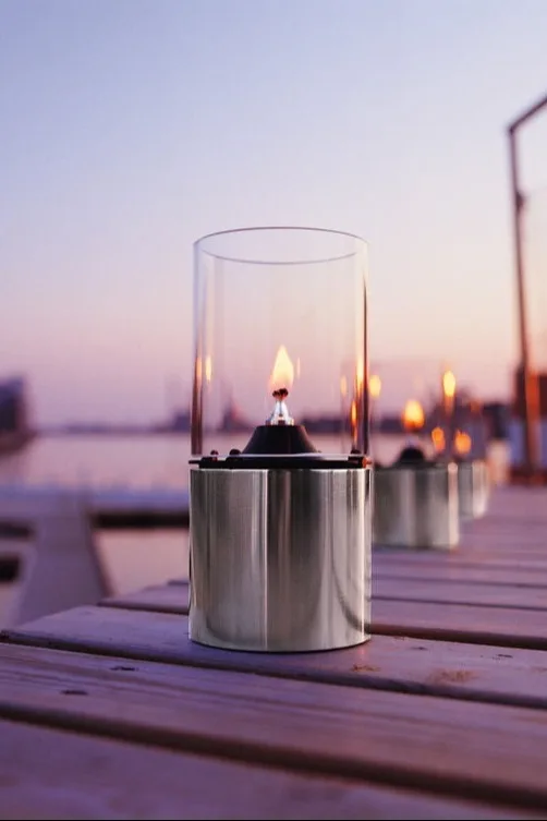 Placer lanterner og vindlys udenfor på din altan, terrasse eller i haven, for eksempel den stilfulde olielampe fra Stelton.