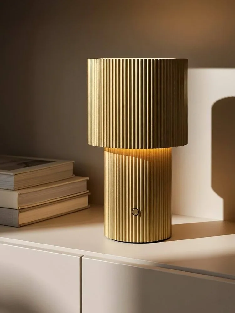 Guldribbet bordlampe, glødende, med en cirkulær knap på foden.