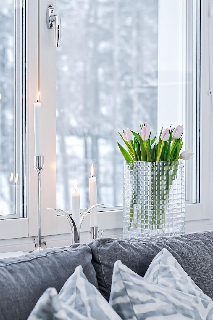 Pynt din vindueskarm med stearinlys eller smukke blomster, især i de mørke måneder. Her ses friske tulipaner i City Hurricane-vasen af Louise Roe ved siden af forskellige sølvlysestager med hvide lys i i vindueskarmen af @josefinsinredning.