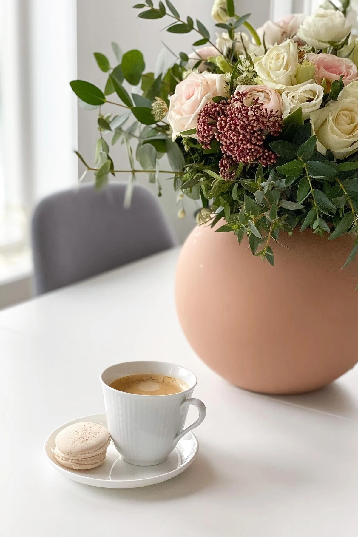 På @helfags spisebord står der kaffe i det lille hvide Swedish Grace-krus fra Rörstrand, og ved siden af står en buket blomster i Ball-vasen fra Cooee Design.