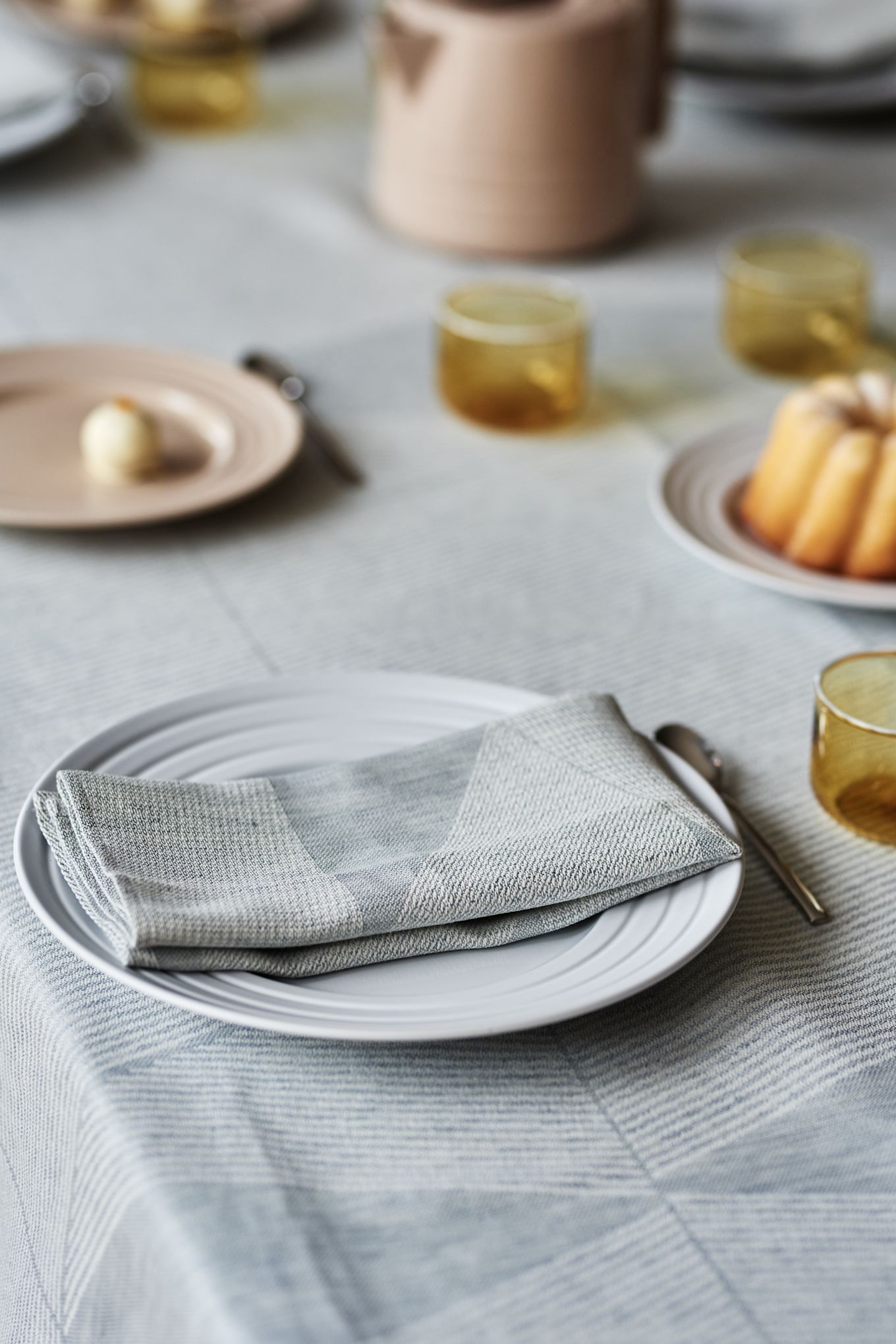 En elegant borddækning ide i bløde pasteller med en himmelblå dug fra NJRD og delikate beige og gule elementer.
