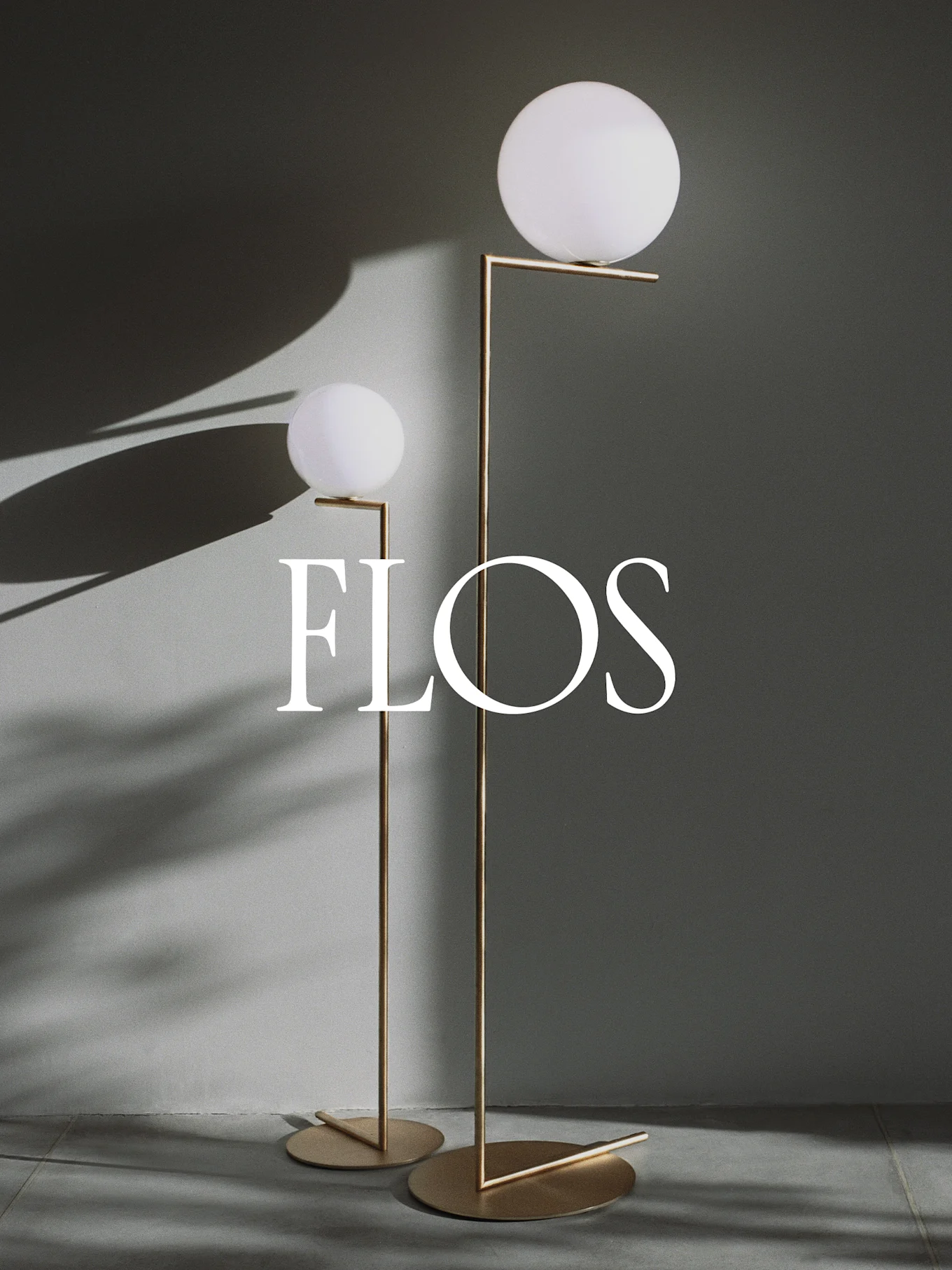 To moderne gulvlamper med sfæriske hvide diffusere og guld metalrammer, med Flos-logoet.