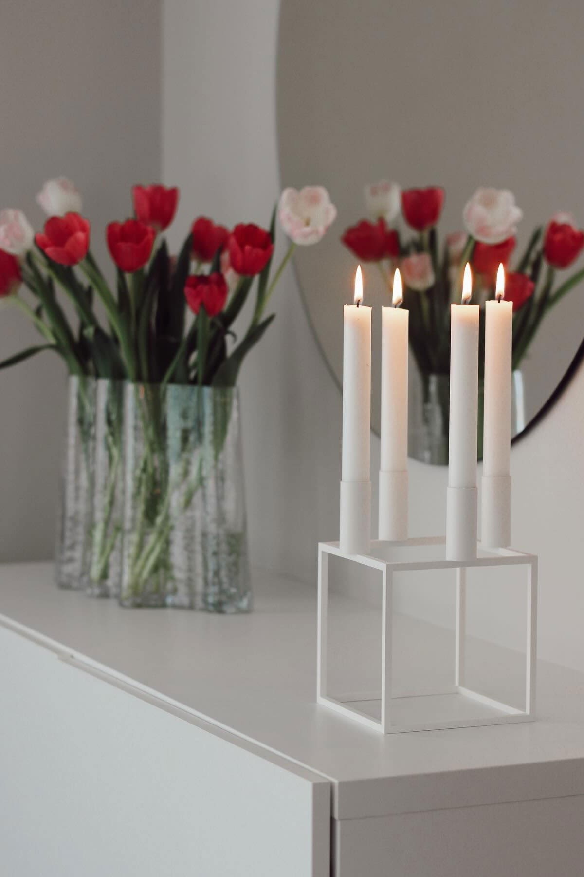 Her er den hvide Kubus-lysestage med fire lys fra Audo Copenhagen på en kommode bag Gry-vasen fra Cooee Design med tulipaner i @susannfrustol's hjem.