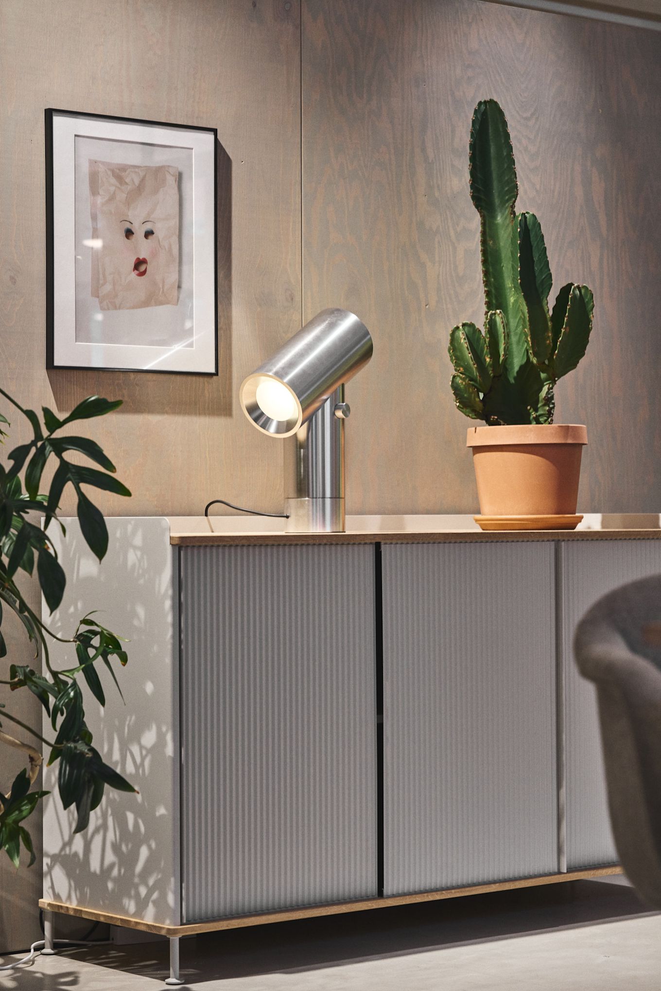 Den sølvfarvede Enfold-kommode fra Muuto med en kaktus på toppen og den sølvfarvede Beam-bordlampe fra Muuto.