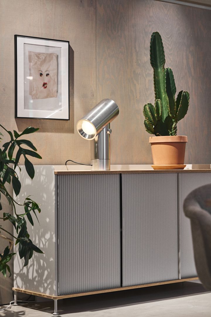 Den sølvfarvede Enfold-kommode fra Muuto med en kaktus på toppen og den sølvfarvede Beam-bordlampe fra Muuto.