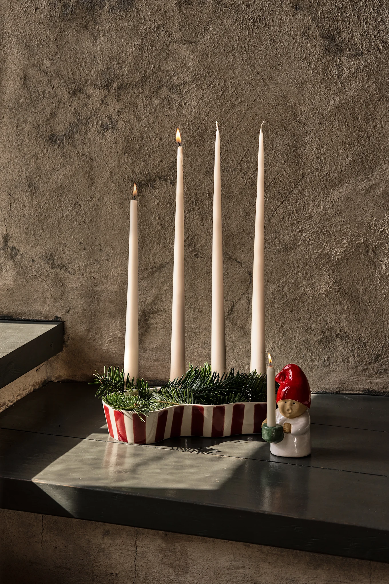 Elegant bord dækket med mørkerød dug, vinglas, tallerkener, et frugtfad og tændte stearinlys.