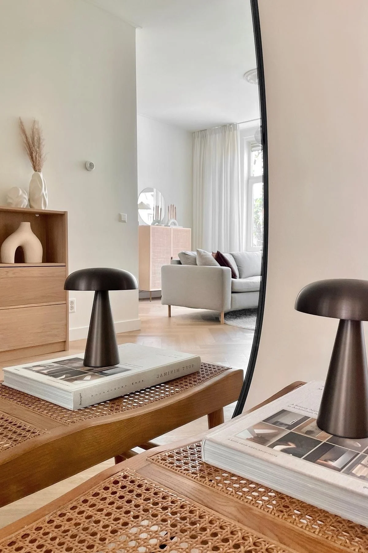 Her kan du se den portable Como lampe fra &Tradition stå på en bog i en ren, oprydet Japandi indrettet stue. 