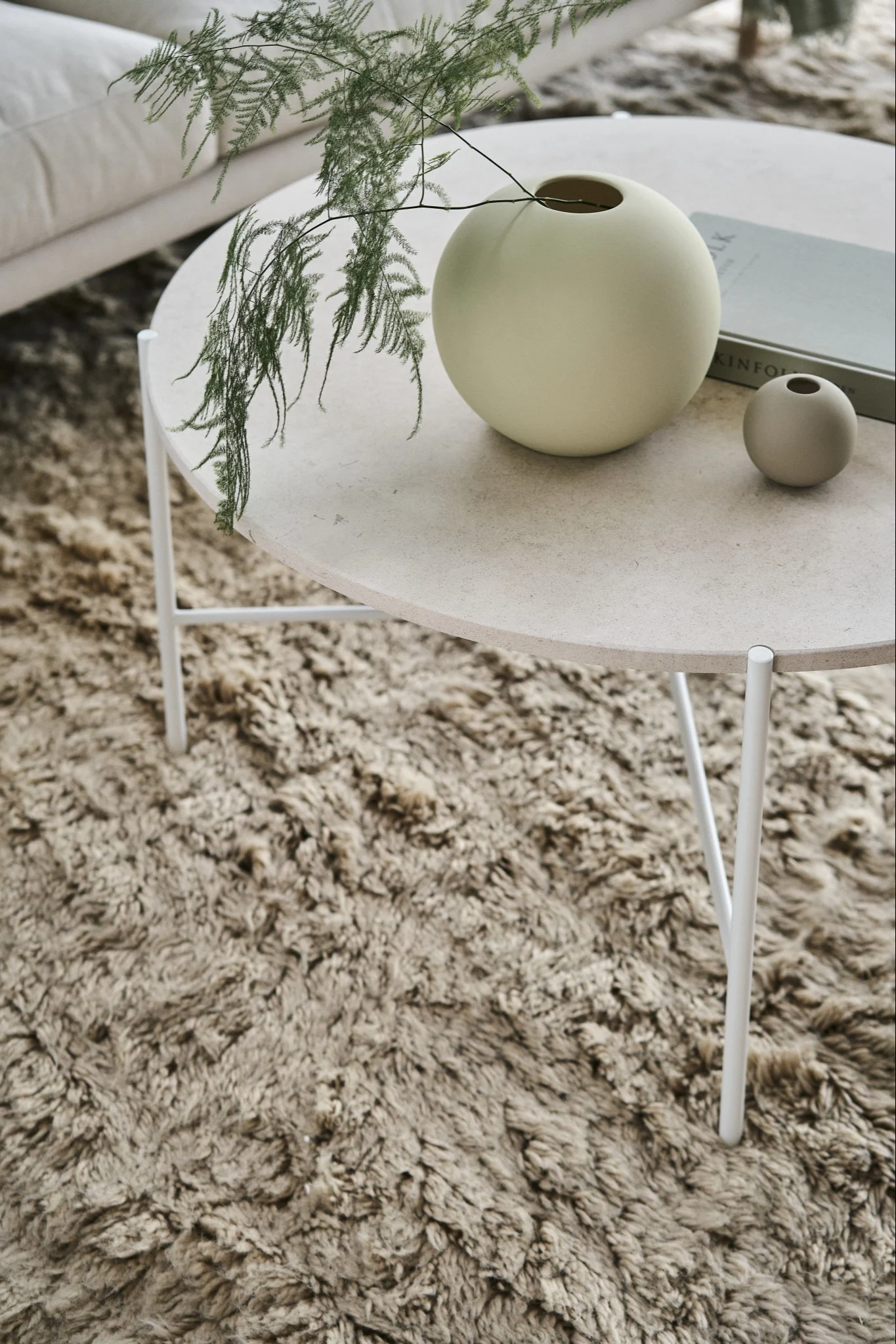 Den ikoniske Ball vase i shell og sand fra Cooee Design på et sofabord i en skandinavisk indrettet stue.