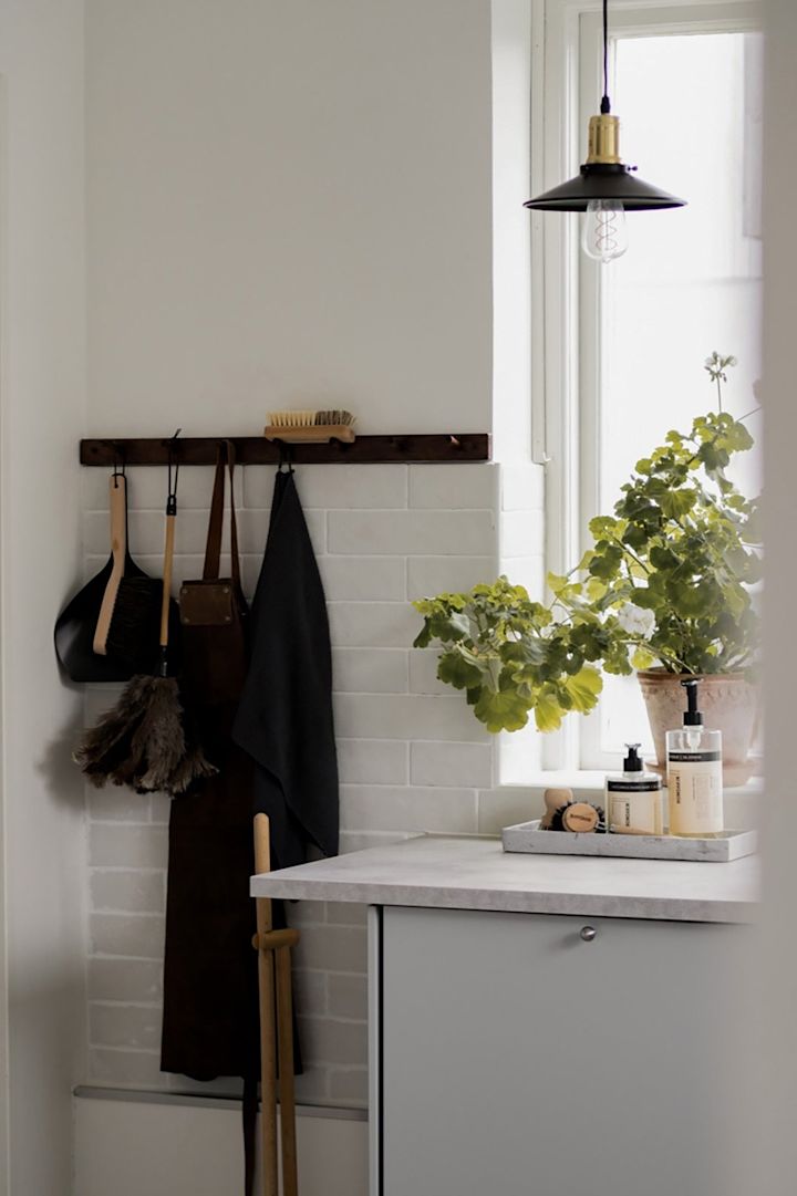 Mindre pendler giver spotbelysning i køkkenet. Her ses Disc Mini pendlen i sort fra Globen Lighting hængende i et køkken foran et vindue.