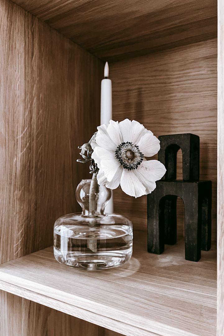 Ideer til boghyldeindretning - inspiration fra Anela Tahirovics hjem @arkihem, hvor en afskåret blomst i en fin Marimekko-vase skaber et mere levende indtryk på din boghylde.