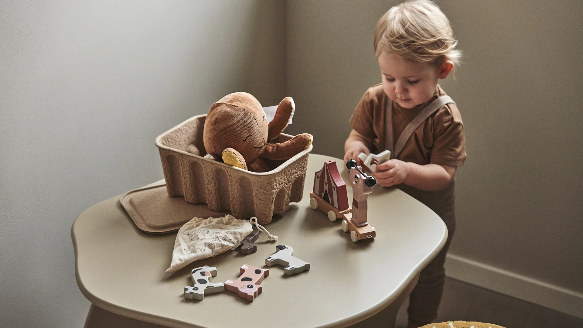 På et børneværelse er det vigtigt at der både er kreative og praktiske ting. Her er et lille barn som leger med klodser på Slope børnebord i beige fra Ferm Living.