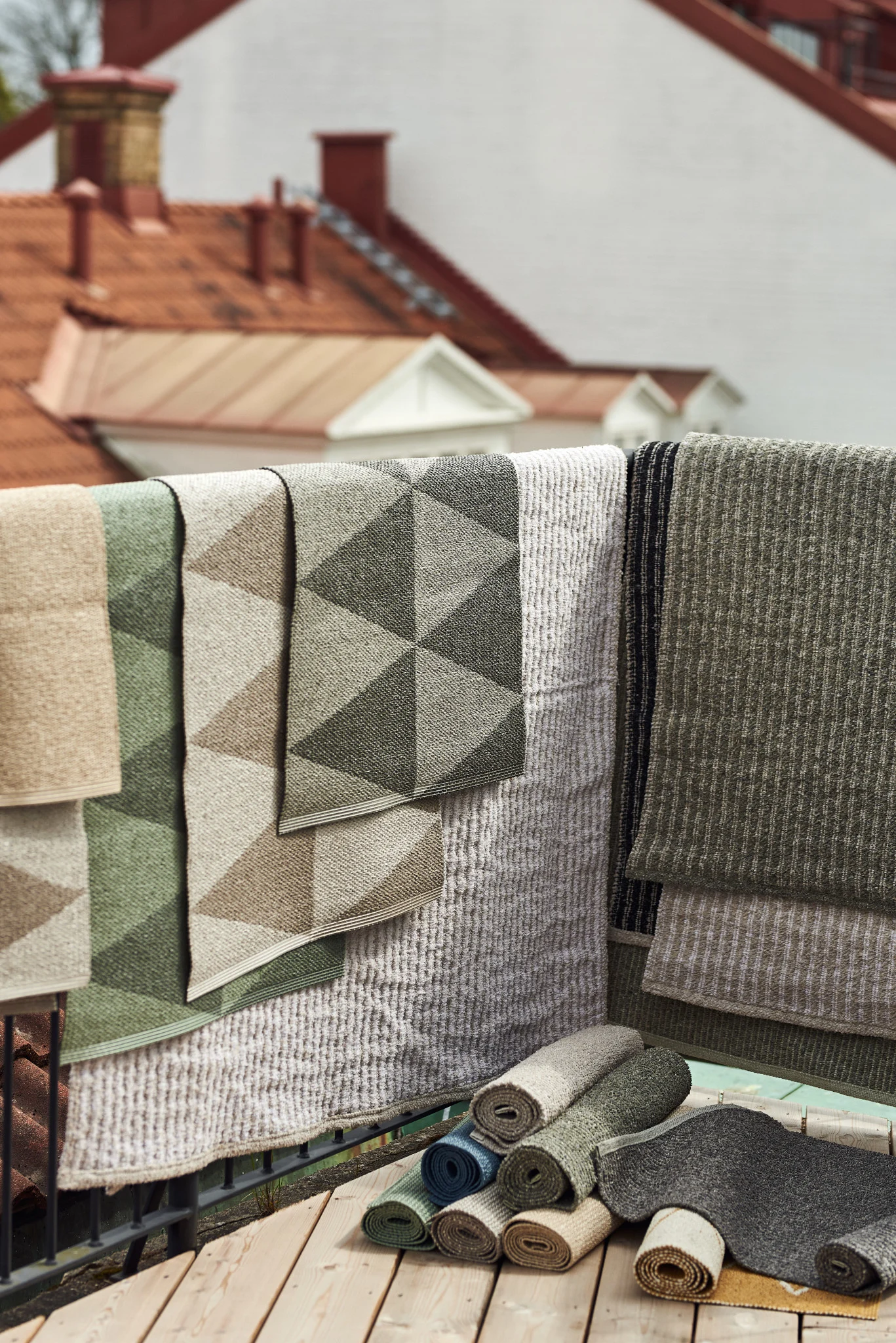 Udendørstæppe: Her ses de mange udendørstæpper fra Scandi Living i forskellige størrelser, materialer og farver hængende over et altanrækværk.