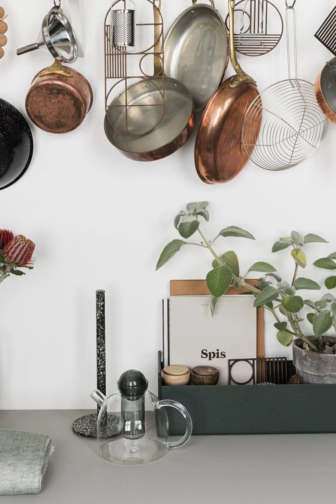 Tekanden Still fra Ferm Living er enkel men stilren, og står her på en køkkenbænk med kasseroller hængende over.